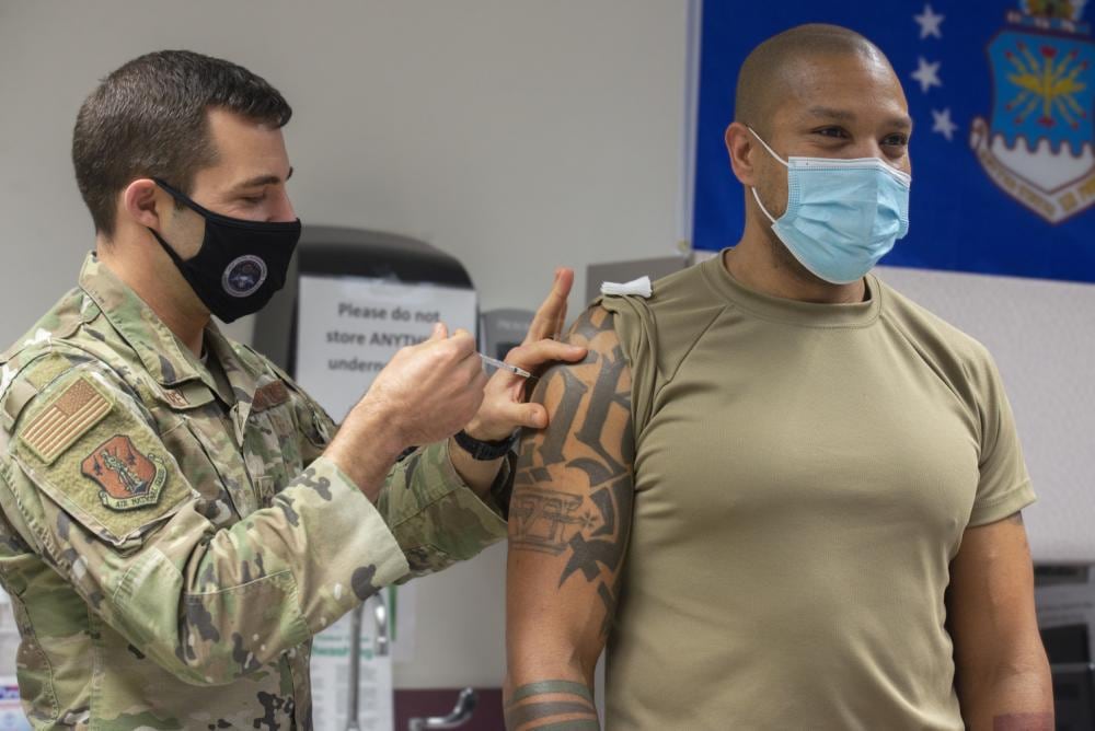 Master Sgt. Jeffrey Delorey, a medic with the 157th Medical Group, gives Tech. Sgt. Alleem Humber, the support section shift lead with the 157th Aircraft Maintenance Squadron, a Moderna booster shot on Dec. 22, 2021 at Pease Air National Guard Base, New Hampshire. Medics administered 80 doses of the booster to airmen who signed up weeks in advance. (Staff Sgt. Victoria Nelson/Air National Guard)