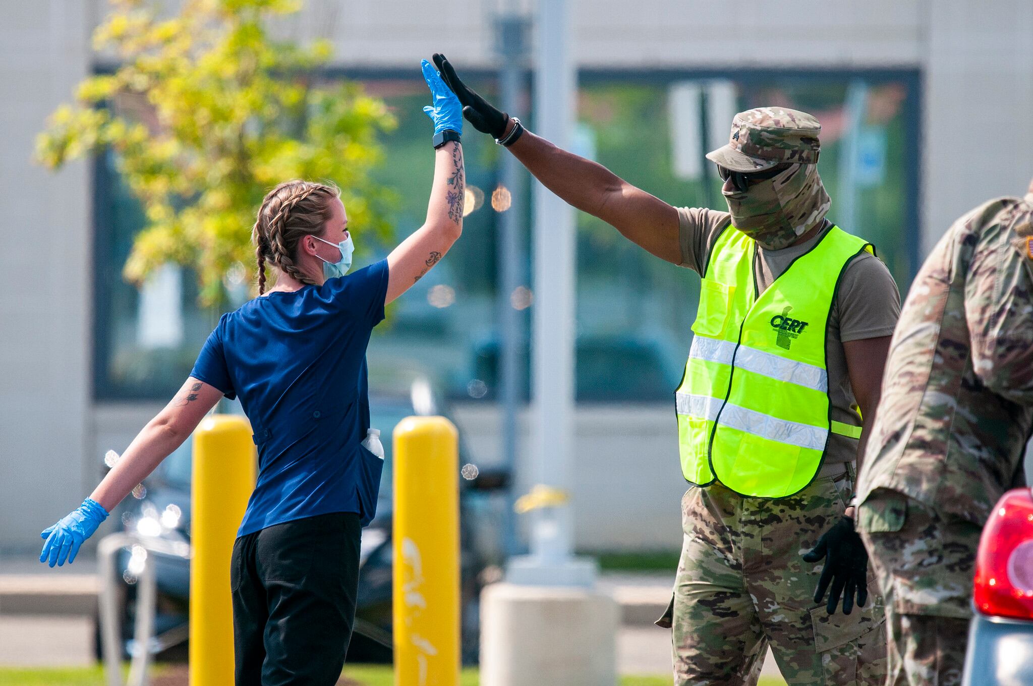 Senior Airman Raelyn Blevins, an aerospace medical technician with the Delaware Air National Guard's 142nd Aeromedical Evacuation Squadron, high-fives Sgt. Zell Flamer, a small arms/artillery repairer with the Delaware Army National Guard's 262nd Component Repair Company, at a drive-thru testing site for COVID-19 on the University of Delaware's Science, Technology and Advanced Research Campus in Newark, Del., July 1, 2020.