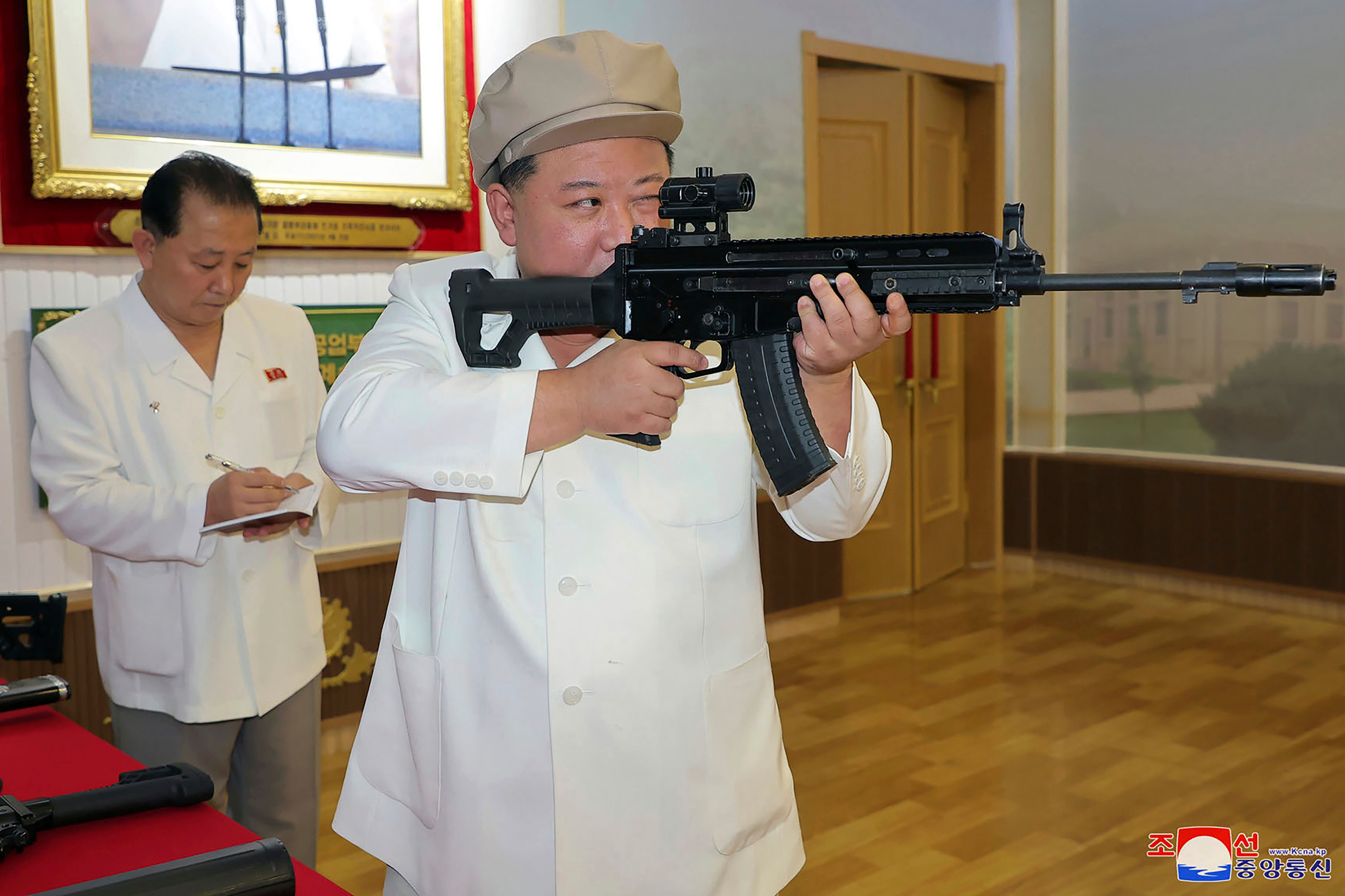 In this undated photo provided by the North Korean government, North Korean leader Kim Jong Un, right, holds a weapon during his three-day inspection from Aug. 3 until Aug. 5, 2023 at major munitions factories in North Korea.