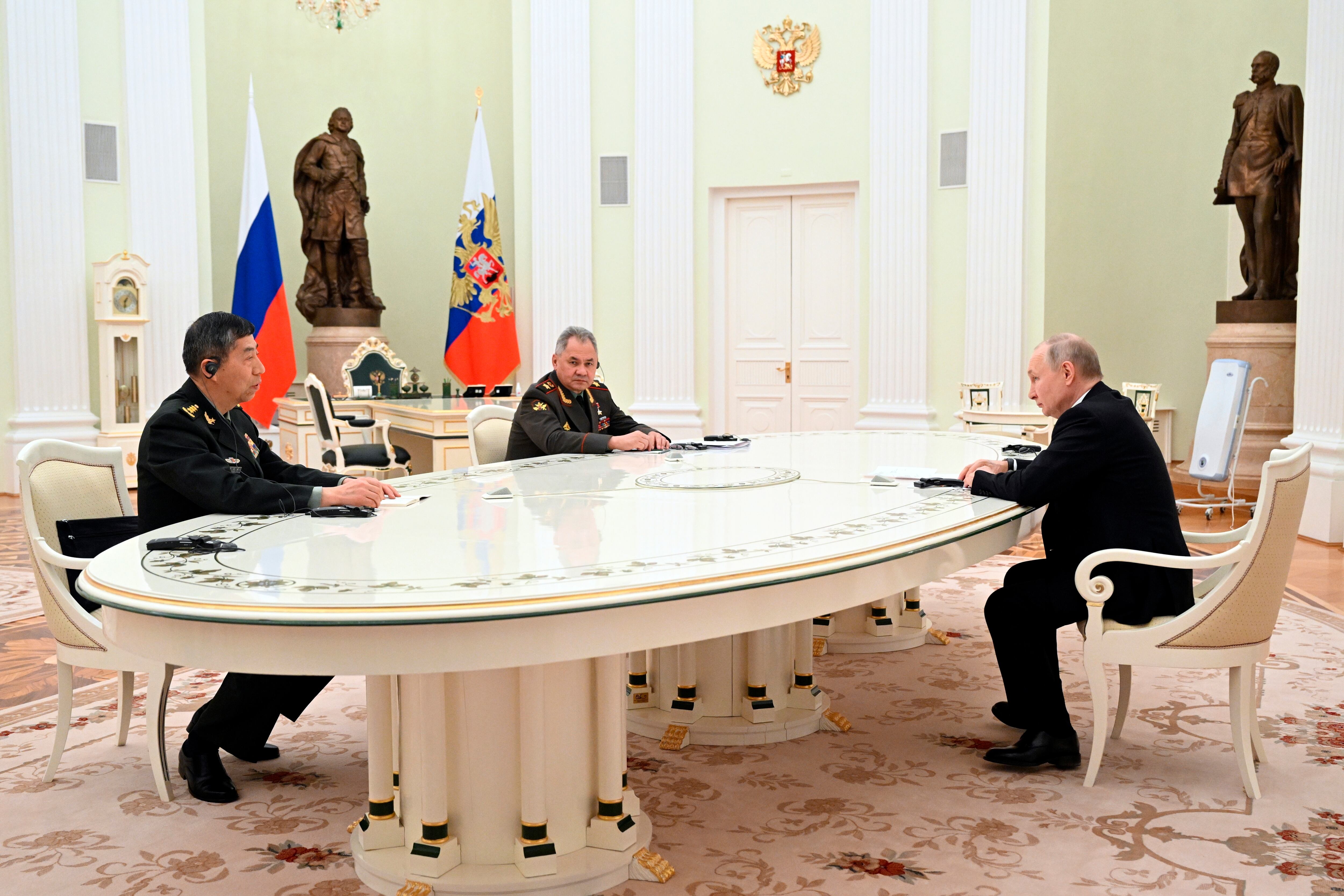 Russian President Vladimir Putin, right, speaks to China's Defense Minister Gen. Li Shangfu, left, and Russian Defense Minister Sergei Shoigu at the Kremlin in Moscow, Russia, Sunday, April 16, 2023.