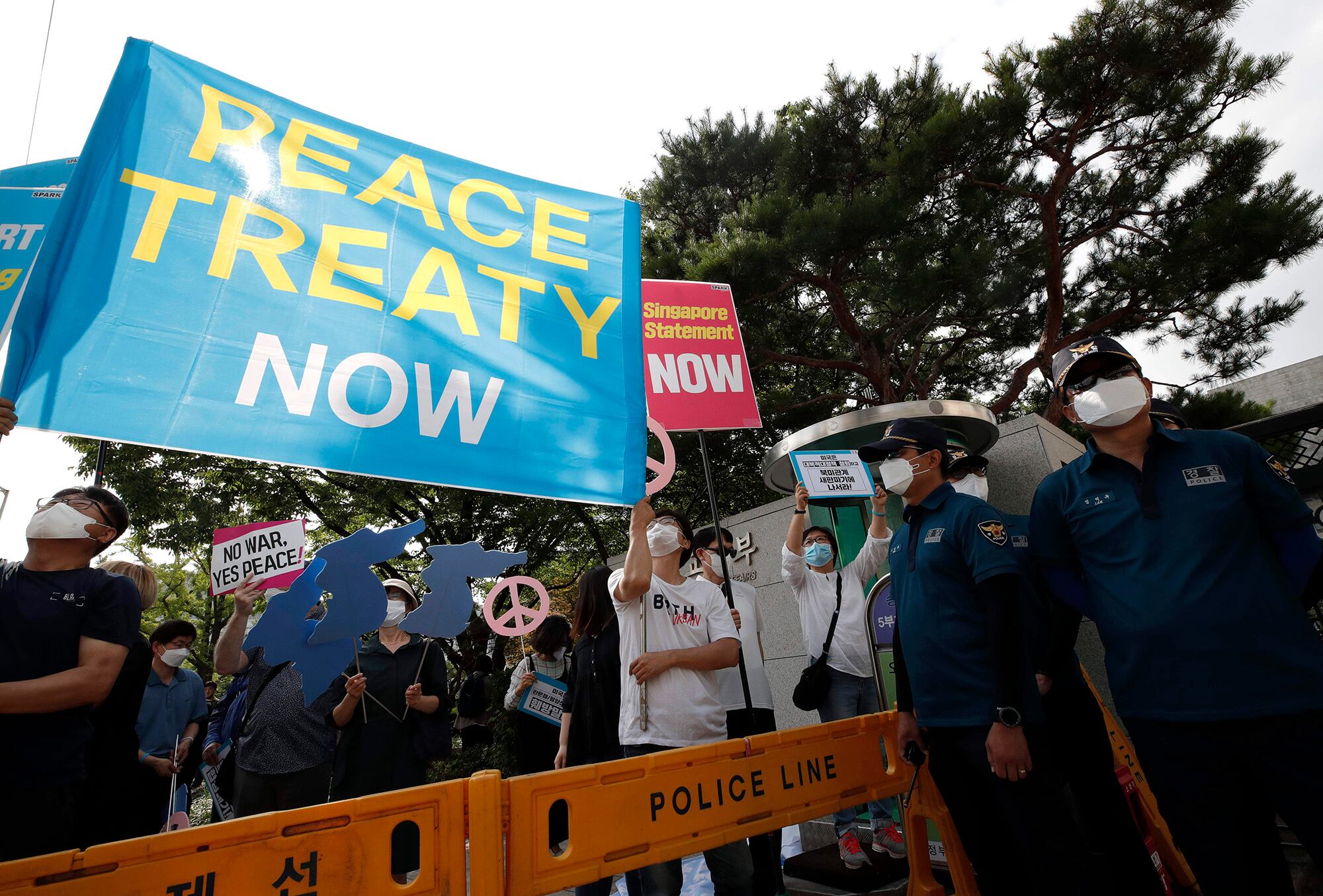 Protesters wearing face masks hold banners as police officers stand guard during a rally to demand the peace on the Korean Peninsula and to stop sanctions against North Korea in front of Foreign Ministry before U.S. Deputy Secretary of State Stephen Biegun's arrival to meet with South Korean officials in Seoul, South Korea, on July 8, 2020.