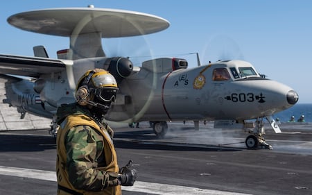 A sailor directs an E-2C Hawkeye on the flight deck aboard the aircraft carrier USS Nimitz (CVN 68) on June 8, 2020, in the Pacific Ocean. (MC3 Elliot Schaudt/Navy)