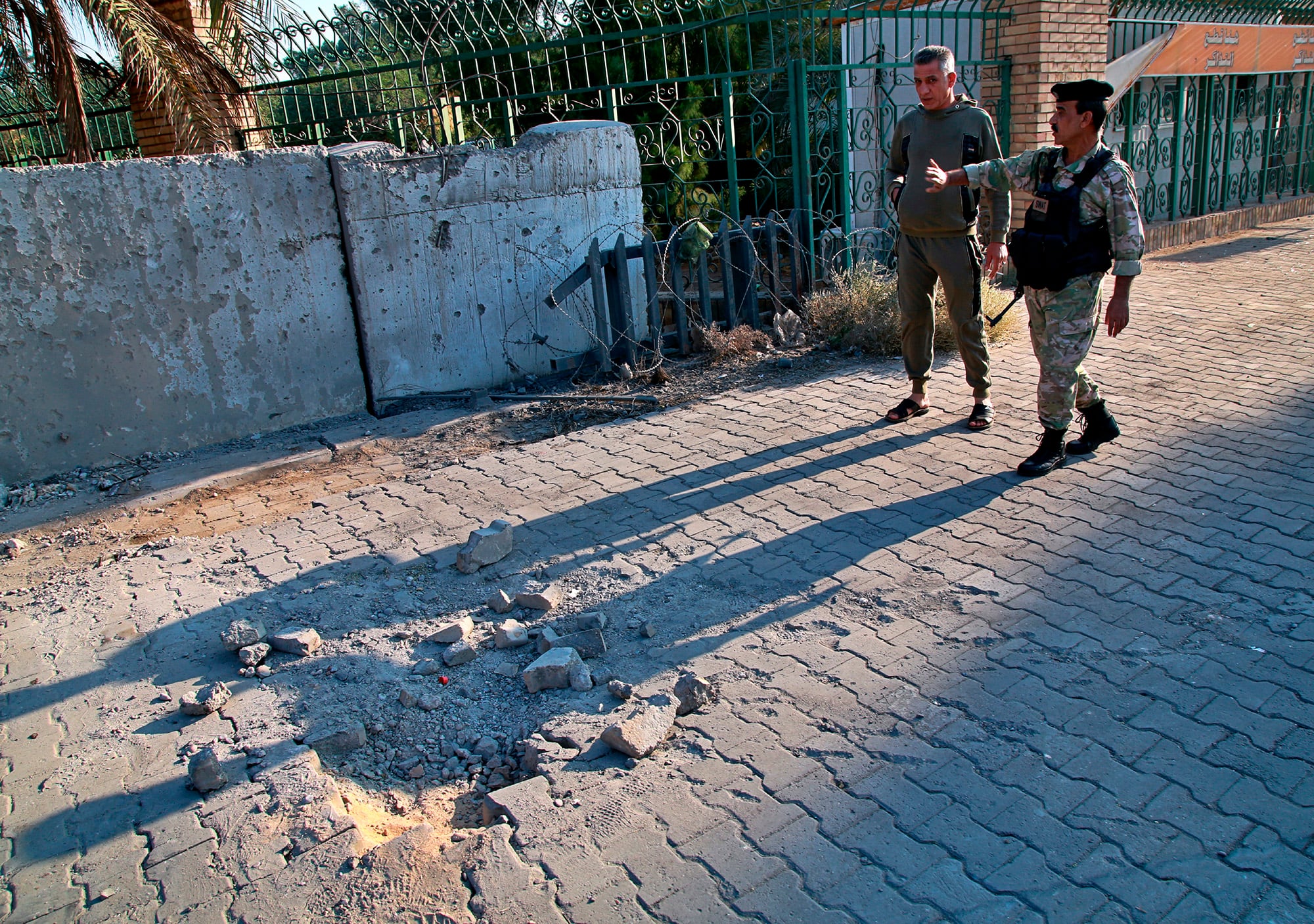 Security forces inspect the scene of the rocket attack at the gate of al-Zawra public park in Baghdad, Iraq, Nov. 18, 2020.