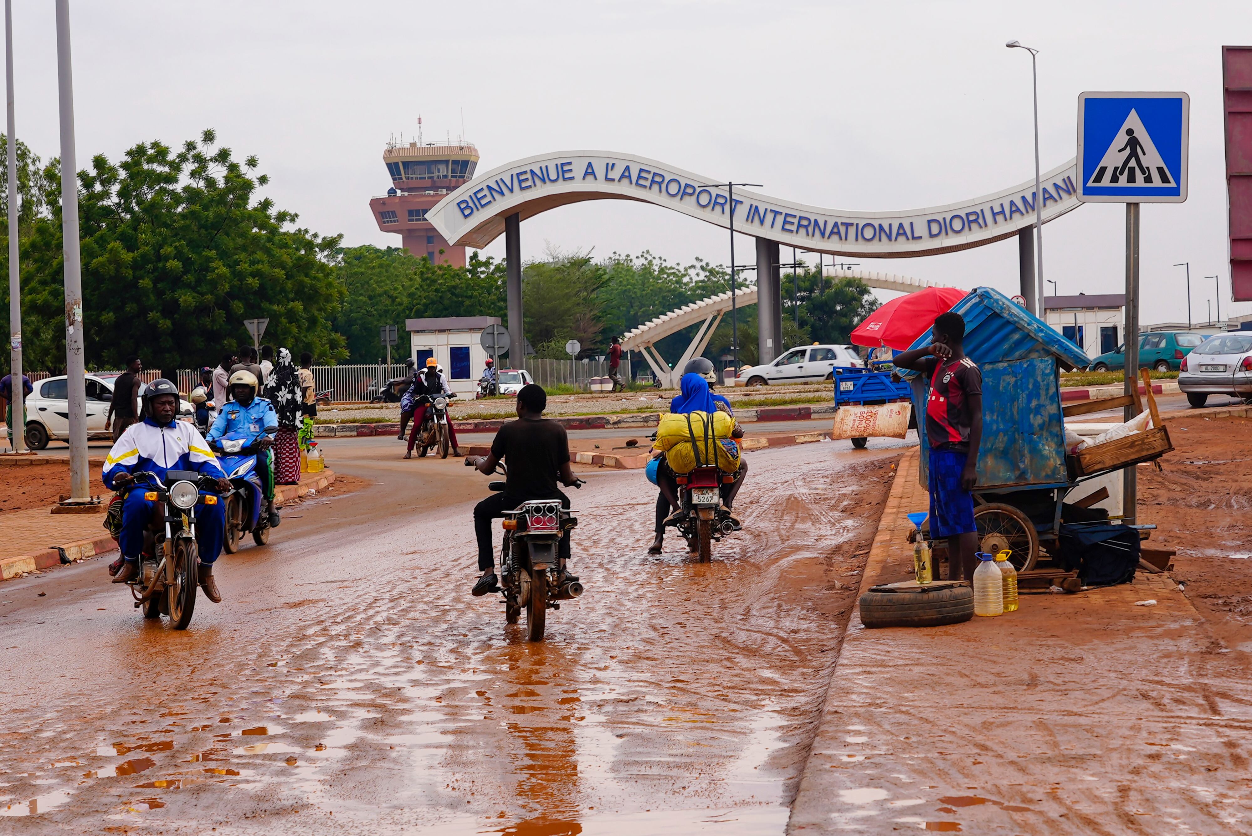 Motorcyclists ride by the entrance of the airport in Niamey, Niger, Tuesday, Aug. 8, 2023.