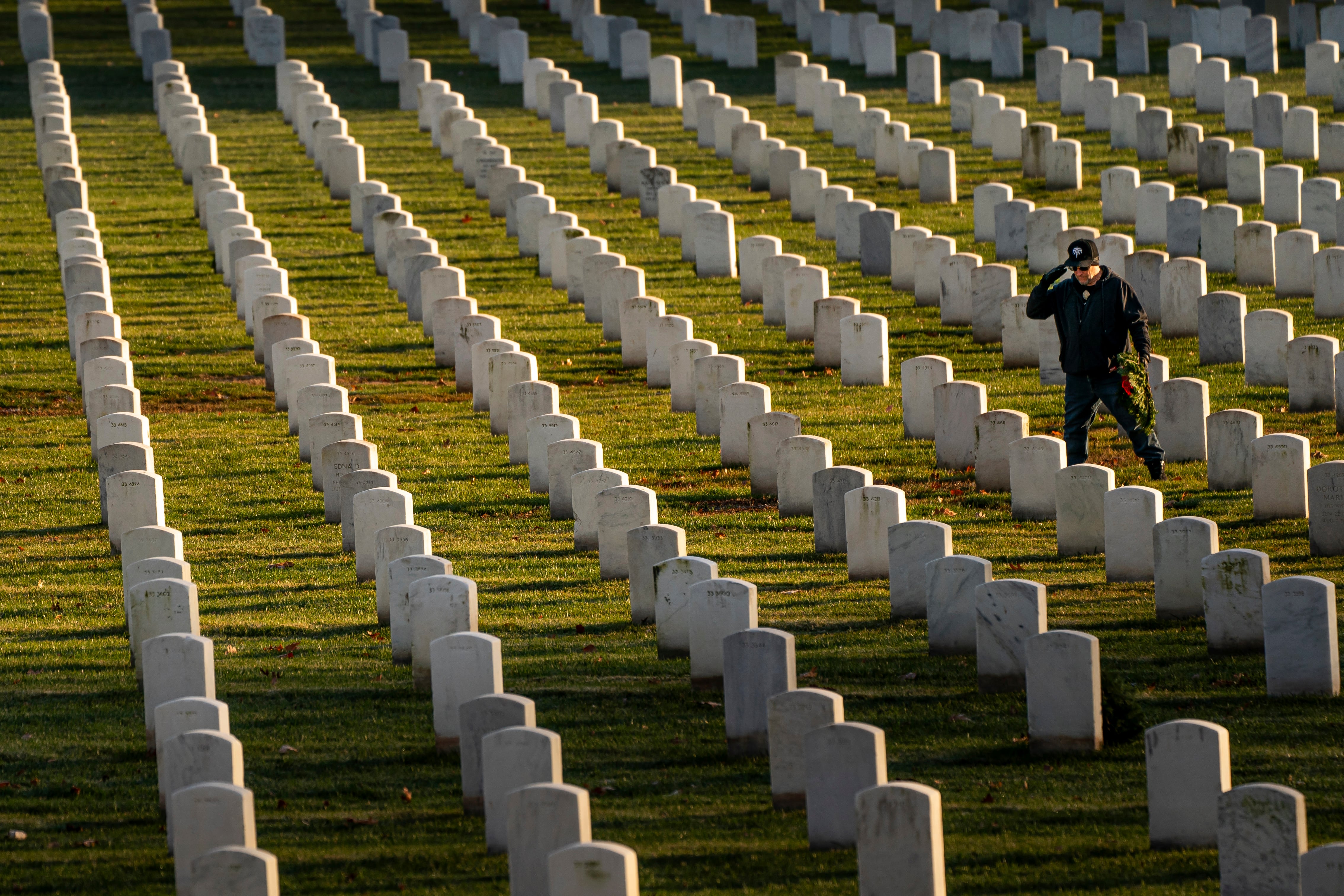 A man salutes after placing a wreath at Arlington National Cemetery, Saturday, Dec. 16, 2023, in Arlington, Va.