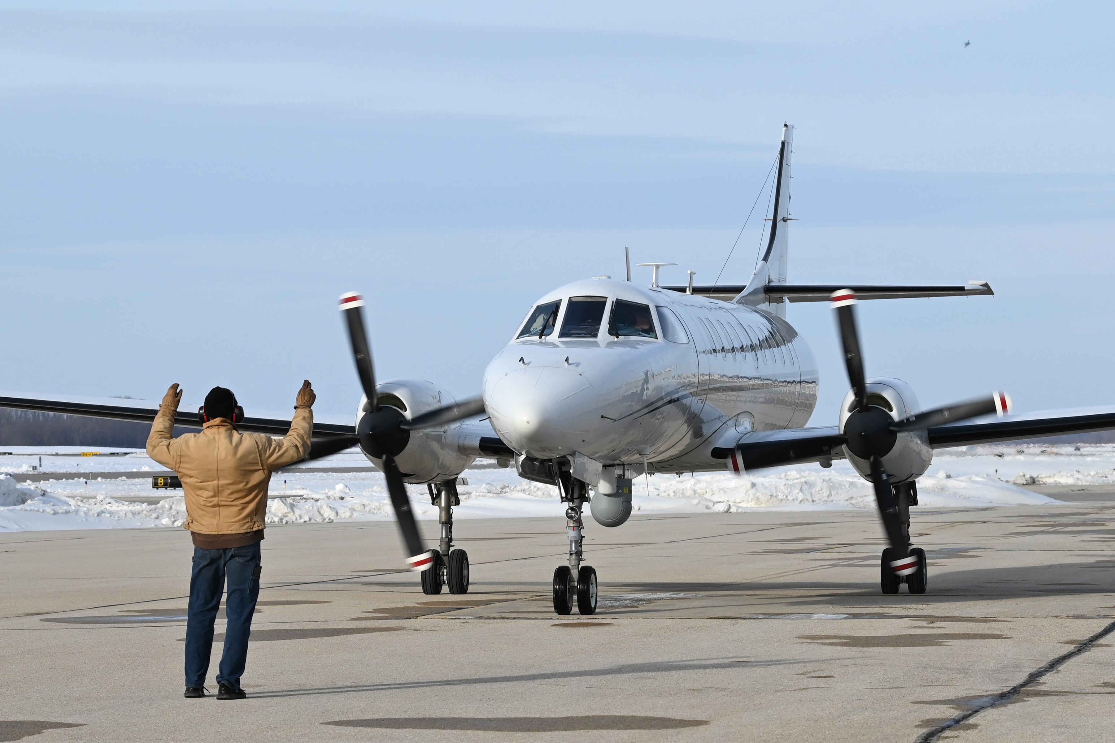 An airman marshals a RC-26 reconnaissance plane