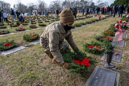 Senior Airman Amber Barkley lays a wreath on a grave at the Delaware Veterans Memorial Cemetery in Millsboro, Del., Dec. 19, 2020.