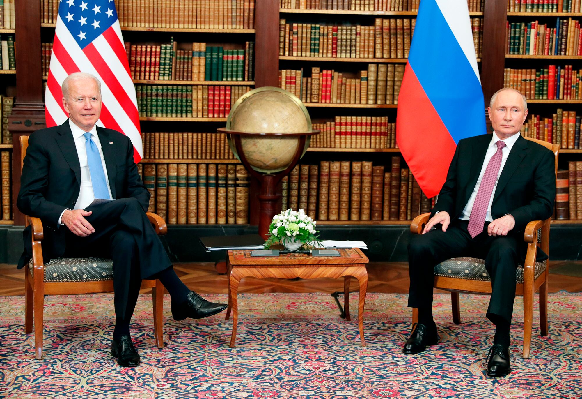 The leaders of the United States and Russia are seated with their nations' flags behind them in a library setting.