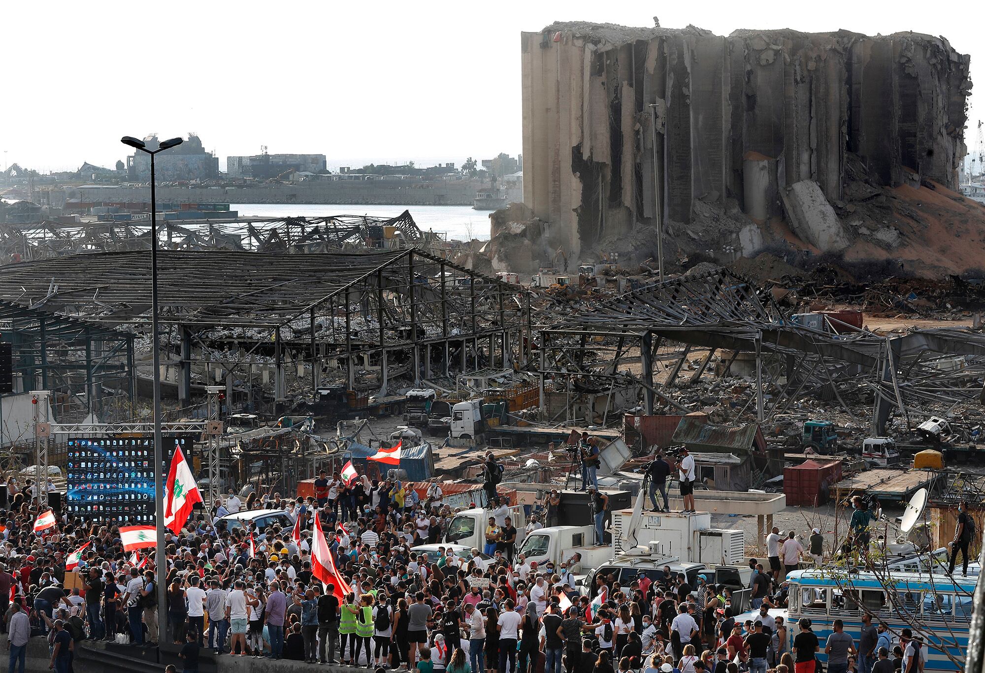 People gather in honor of the victims at the scene of the last week's explosion that killed many and devastated the city, in Beirut, Lebanon, Tuesday, Aug. 11, 2020.