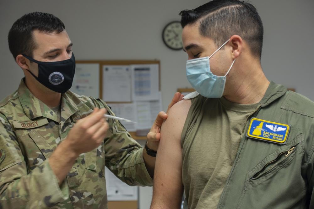 Master Sgt. Jeffrey Delorey, a medic with the 157th Medical Group, gives Tech. Sgt. Ravi Madahar, a boom operator with the 157th Operations Group, a Moderna booster shot Dec. 22, 2021 at Pease Air National Guard Base, New Hampshire. (Staff Sgt. Victoria Nelson/Air National Guard)