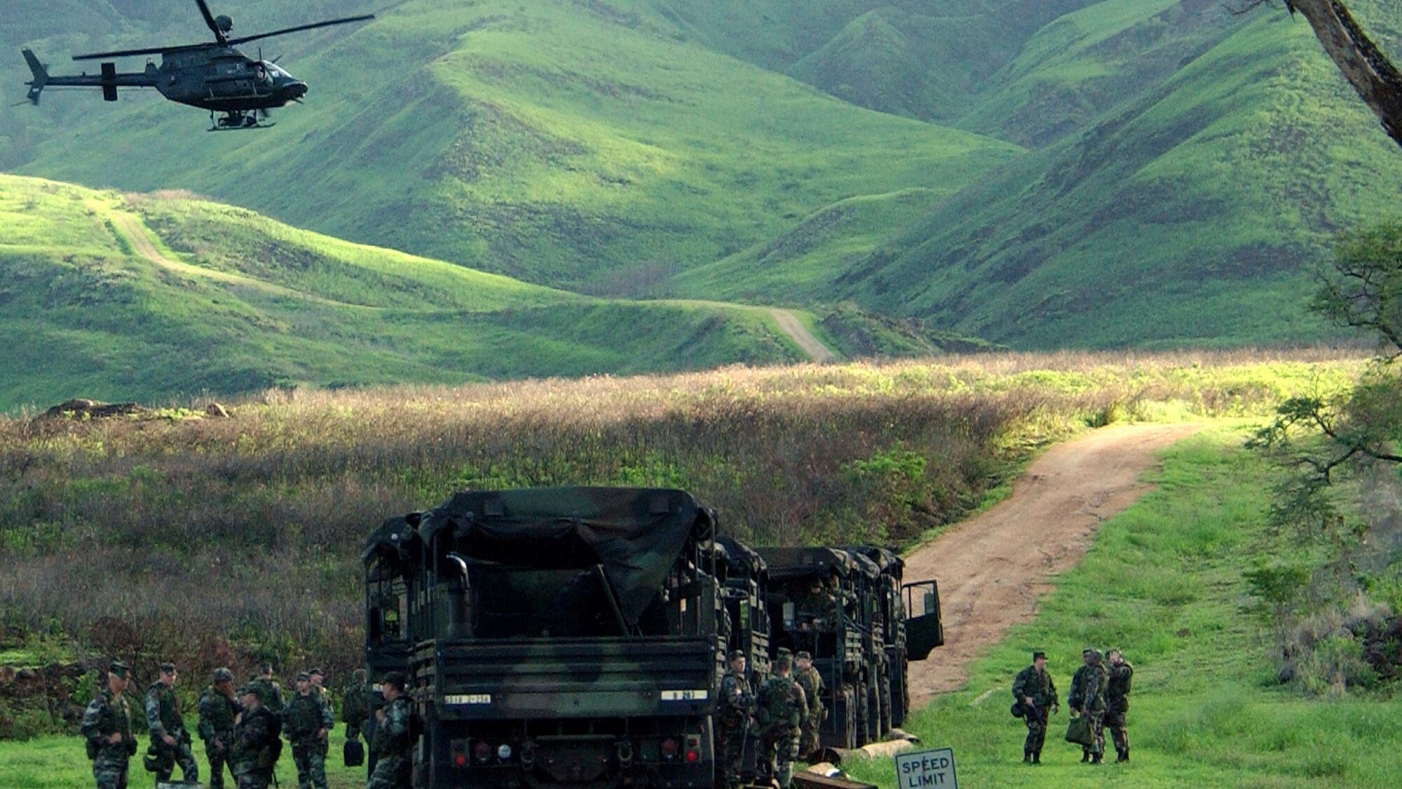 An Army Kiowa helicopter flies over a convoy of U.S. soldiers at the Makua Military Reservation in Hawaii, Dec. 8, 2003.