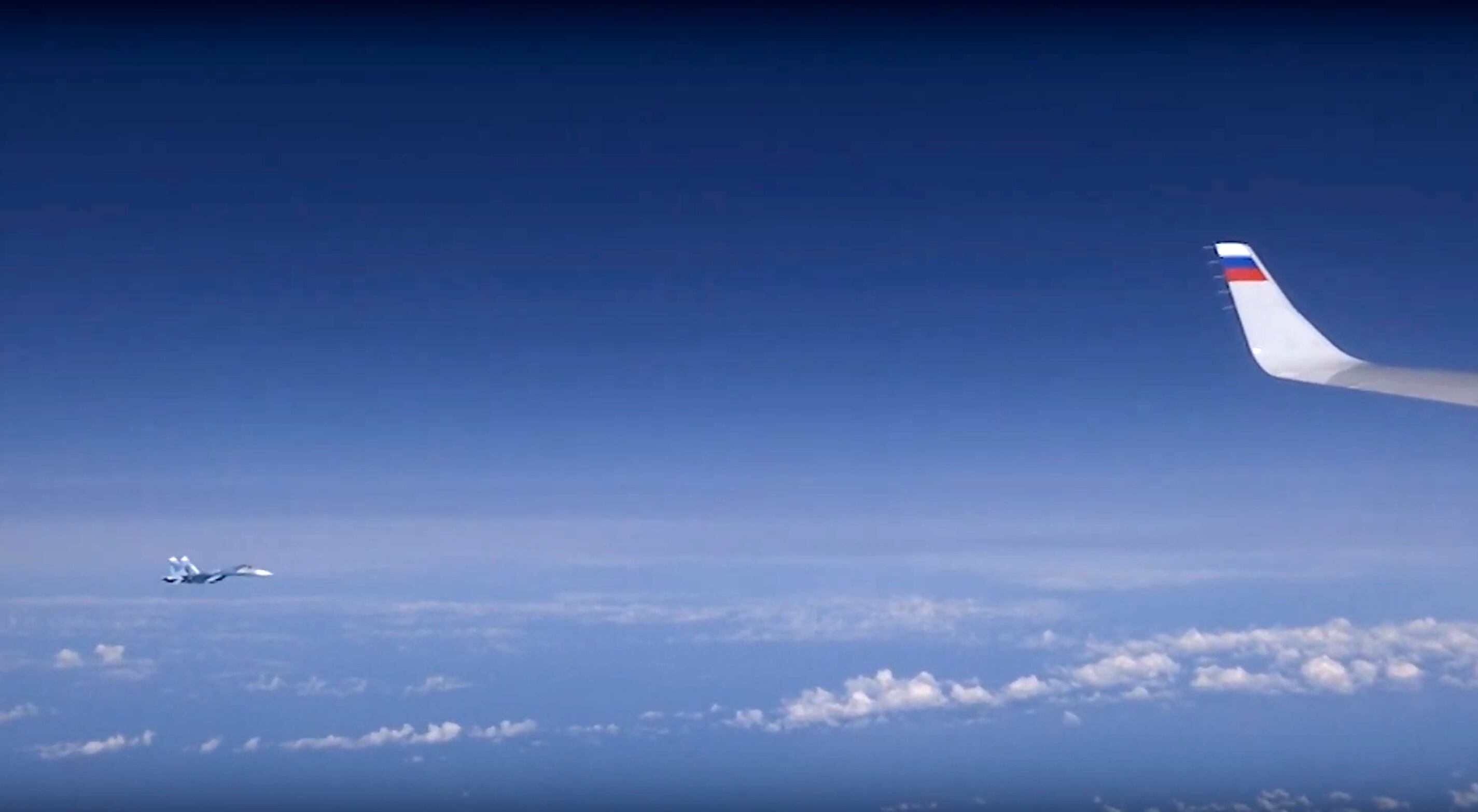 In this video grab taken from a footage on Aug. 13, 2019, and distributed by Russian Defense Ministry Press Service, a view of Russian air force's Su-27 fighter jet, seen from the window of a passenger plane carrying Russian Defense Minister Sergei Shoigu over the Baltic Sea.