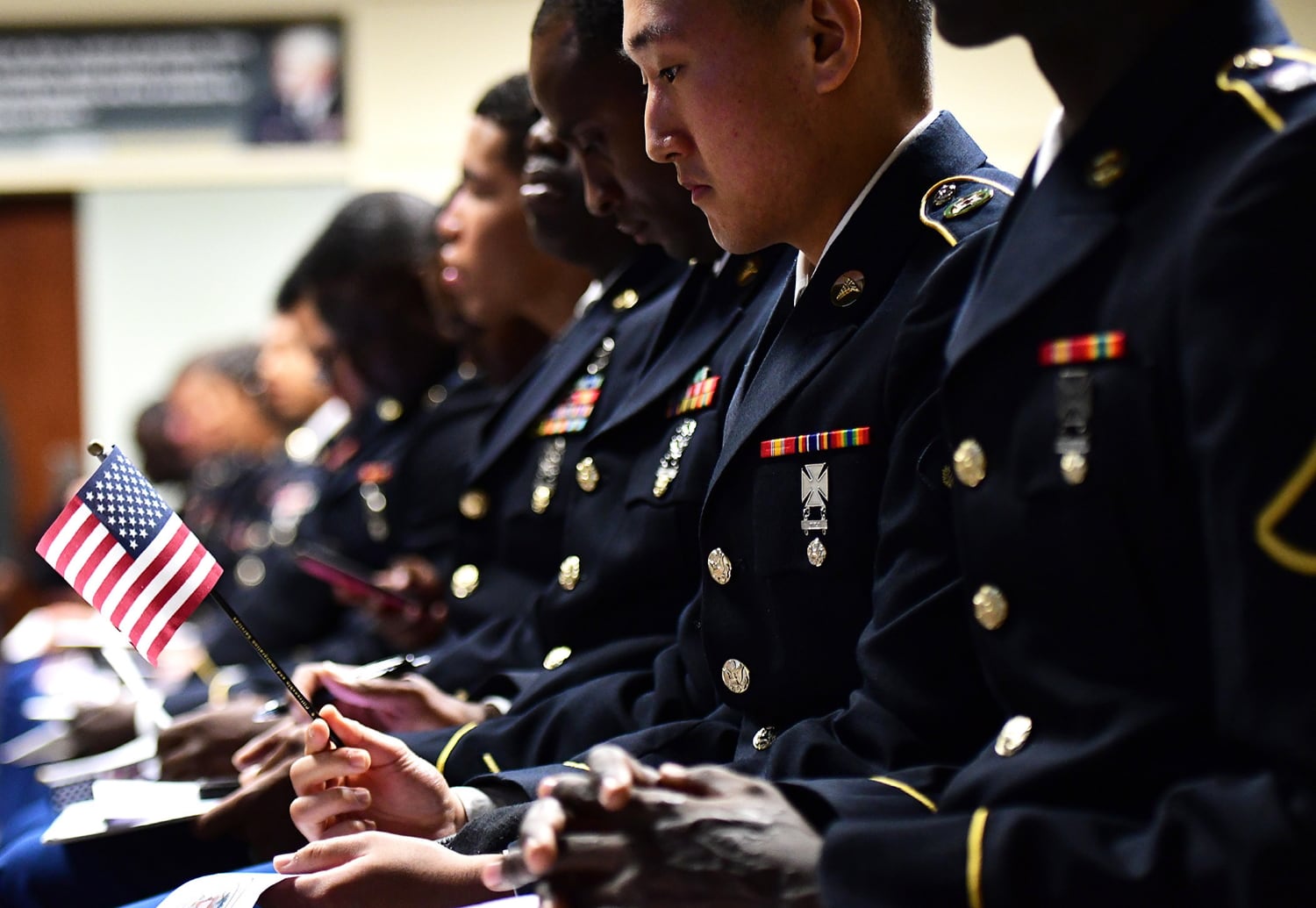 A soldier holds an American flag prior to the start of an oath of citizenship ceremony in the General George Patton Museum's Abrams Auditorium at Fort Knox, Ky., Sept. 19, 2018.