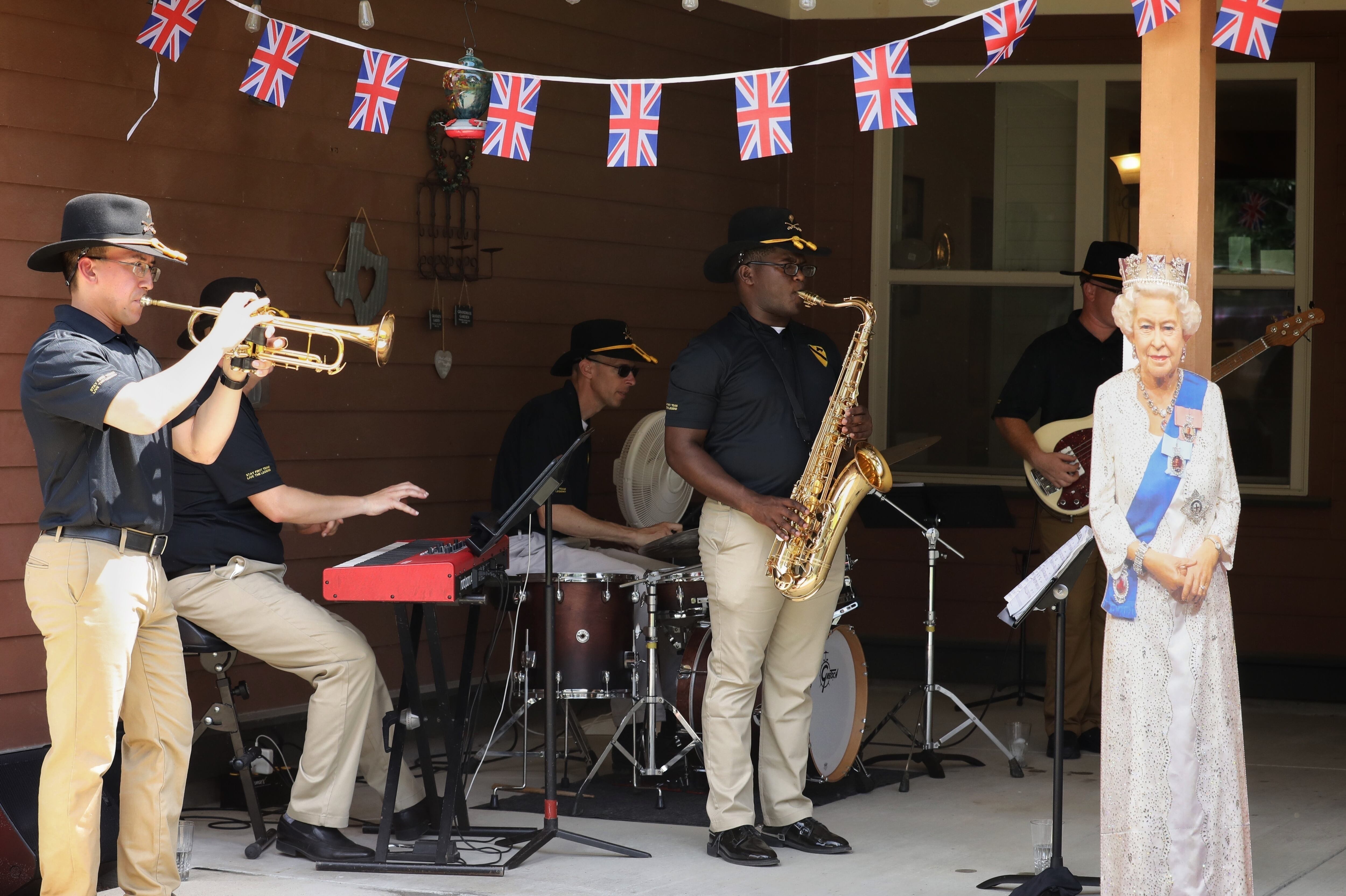 The 1st Cavalry Division Band performs during the Platinum Jubilee celebration for the Queen of England, Elizabeth II, at Fort Hood, Texas, Jun. 4, 2022, with a  cardboard cutout of the queen.