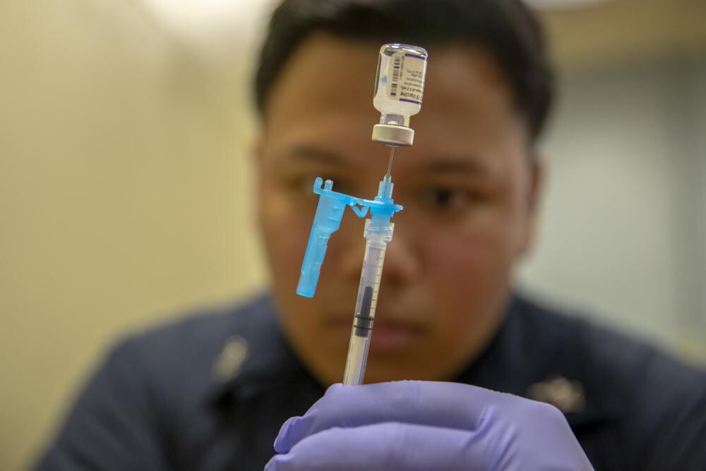 Hospital Corpsman 2nd Class Gregzon Fontanilla, from Guam, prepares a COVID-19 vaccine aboard amphibious assault carrier USS Tripoli (LHA 7), May 10, 2022. (Mass Communication Specialist 2nd Class Malcolm Kelley/Navy)