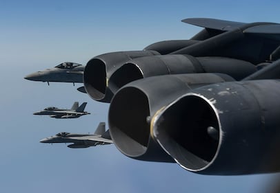 Navy F-18 Hornets form up off the wing of a B-52H Stratofortress over the Arabian Sea for a joint exercise.