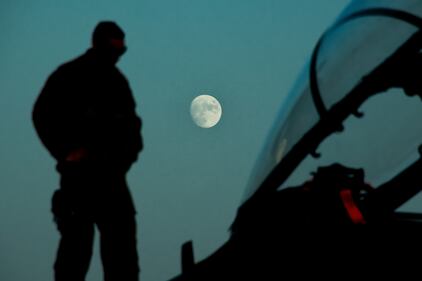 A maintainer deployed to the 332d Air Expeditionary Wing, checks an F-15E Strike Eagle during a routine post flight inspection Sept. 29, 2020, as the moon rises over the flightline in an undisclosed location.